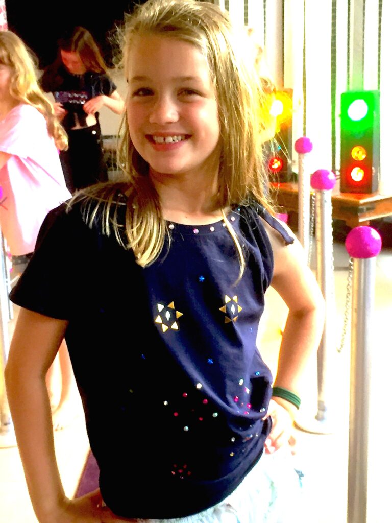 Girl smiling to camera whilst wearing the t-shirt she has just designed.