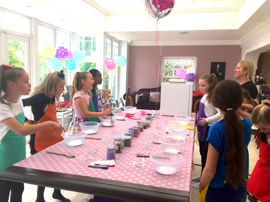 Bath-bomb and soap making party for a girls birthday party. Girls stood around a table getting ready to make their bath-bombs.