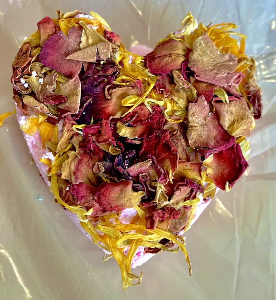 peach coloured heart shaped bath-bomb with dried marigold and rose petals