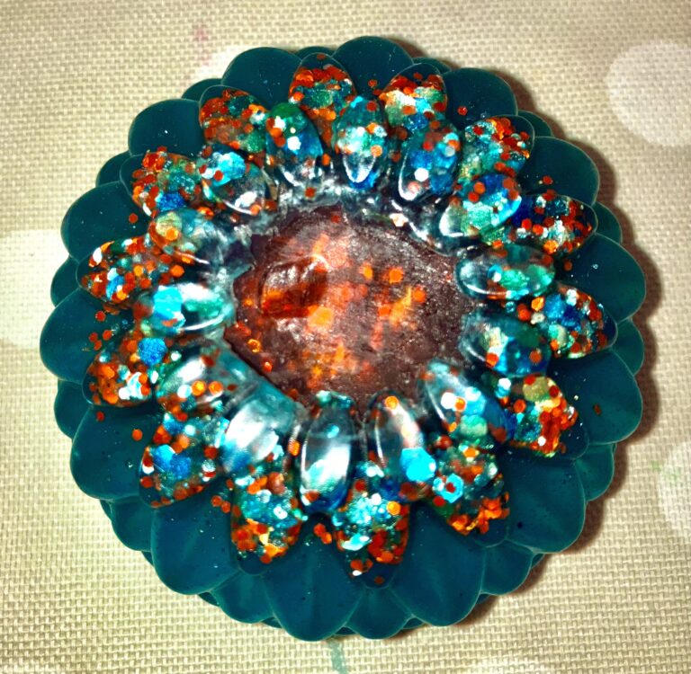 Aqua coloured flower glittery soap with a red center.