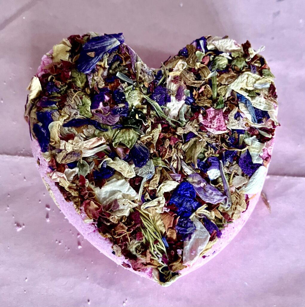 Pink heart shaped bath bomb with dried larkspur flowers