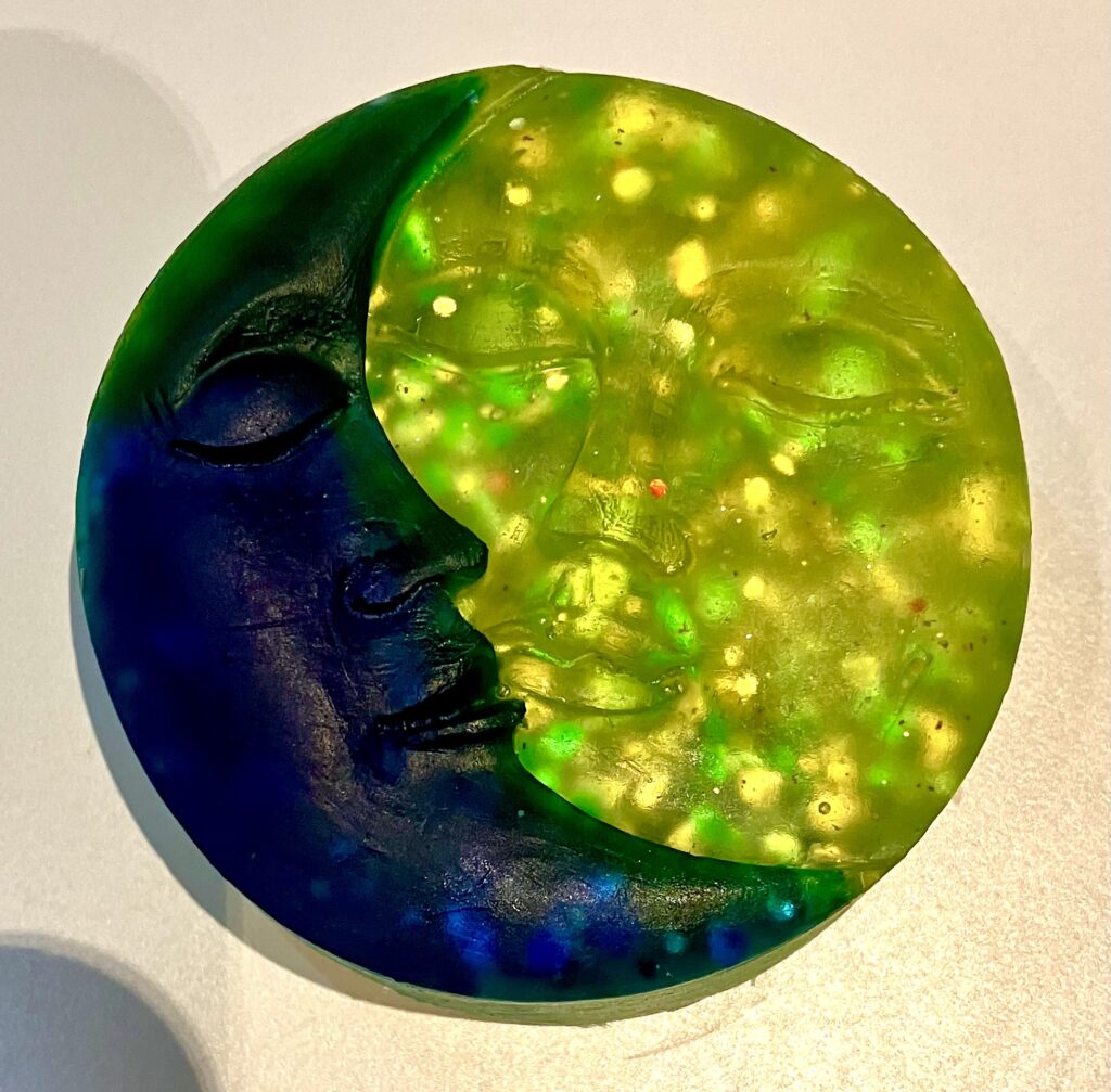 A soap which is half moon and half sun. The moon is dark blue and the sun a glittery yellow.
