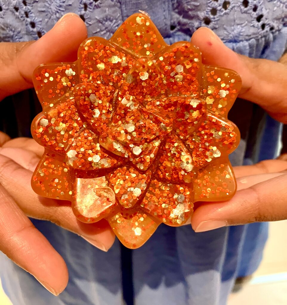 Orange glittery flower soap being held either side.