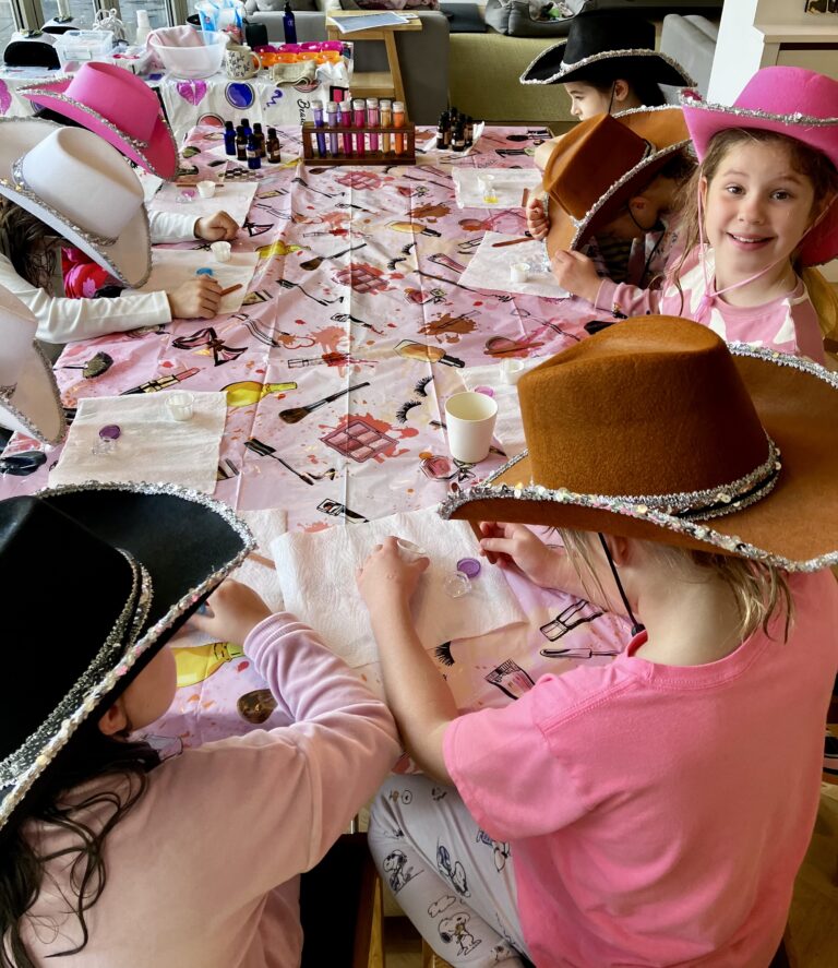 Girls sat around a table making a lip balm gloss at a Giddy Diva spa party.