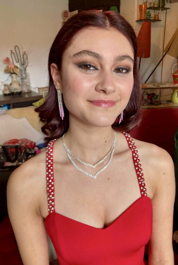 Girl in red dress smiling to camera ready to go to her prom.