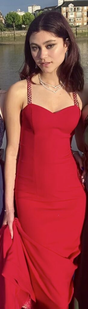 Girl looking sultry posing to camera in full length red dress.