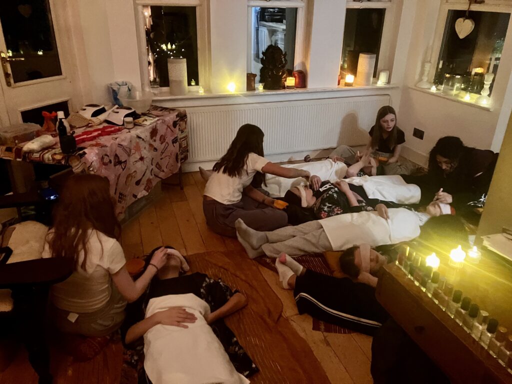 Spa party under candle light, Girls lying down and their partners are applying their face mask to them.