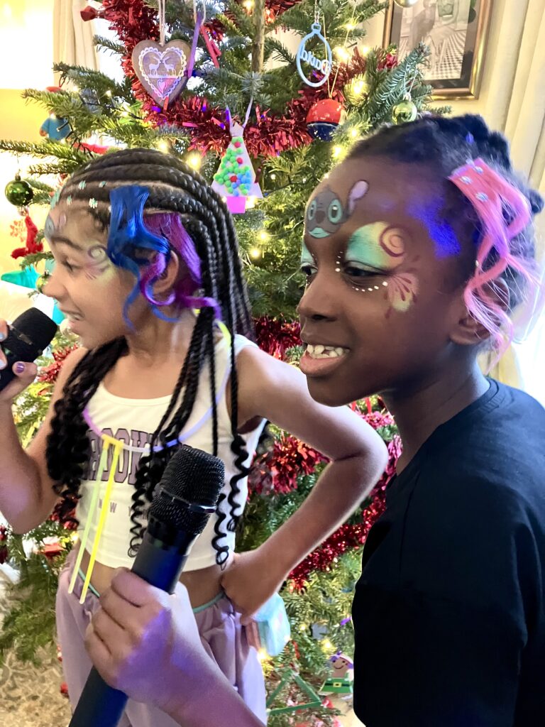 Two girls with face paint singing into wireless mics.