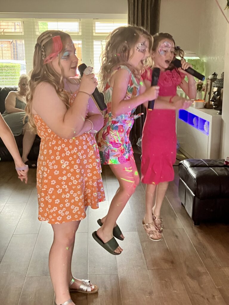 Three girls singing to karaoke and jumping in the air.